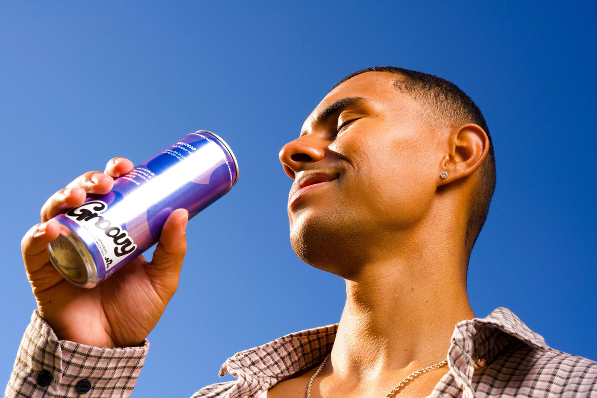 A man drinking a Groovy Nightcap can under a blue sky